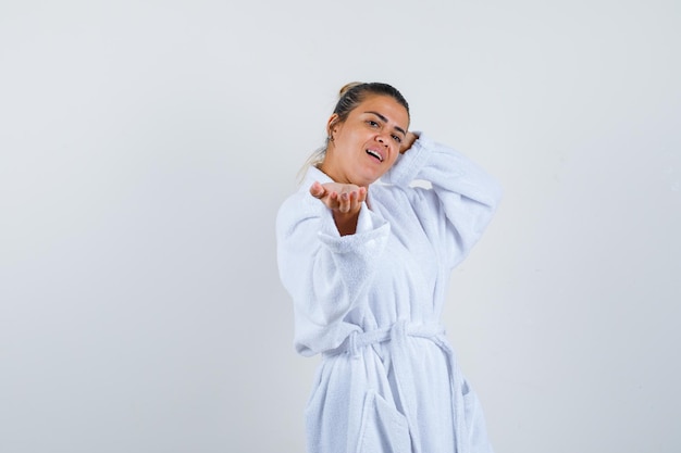 Young lady in bathrobe pretending to show something and looking confident