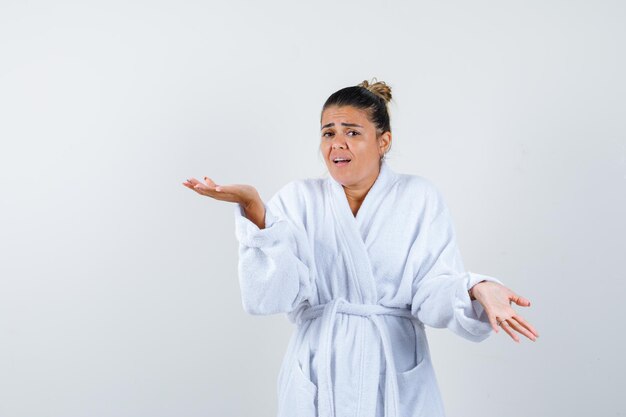 Young lady in bathrobe stretching hand in questioning gesture and looking dissatisfied