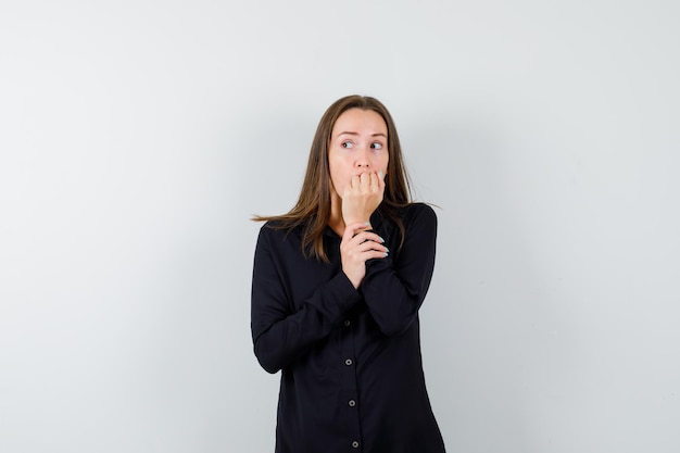 Young lady biting nails and looking anxious