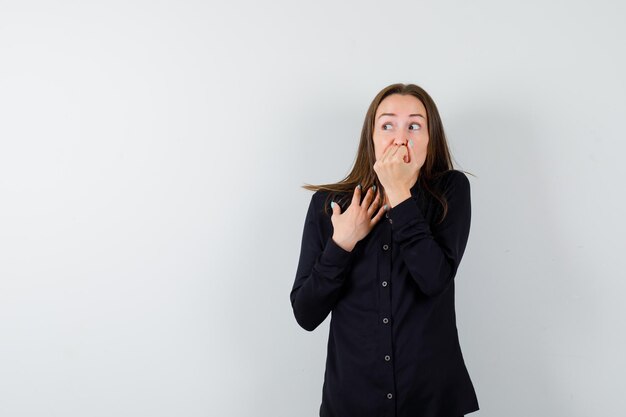 Young lady biting nails and looking scared