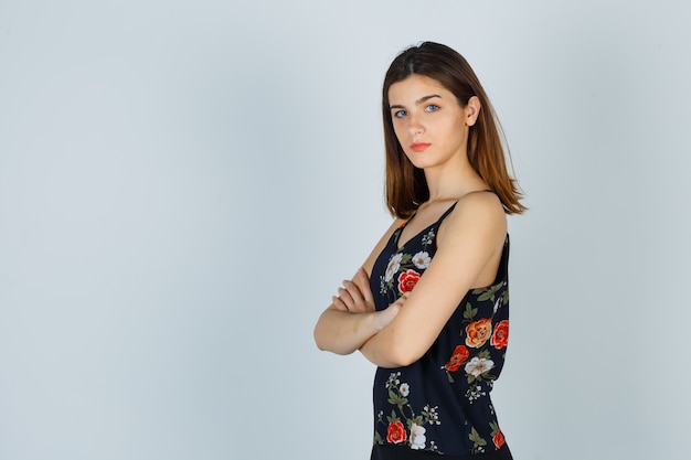 Young lady in blouse holding arms folded and looking confident .