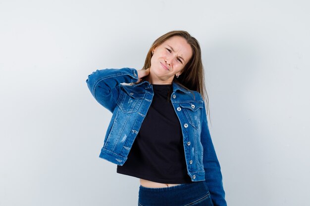 Young lady in blouse, jacket suffering from neck pain and looking tired