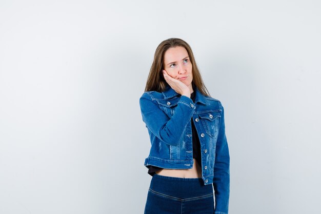 Young lady in blouse leaning cheek on palm and looking pensive , front view.