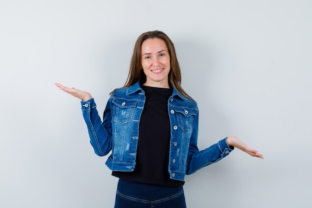 Young lady in blouse making scales gesture and looking confident , front view.