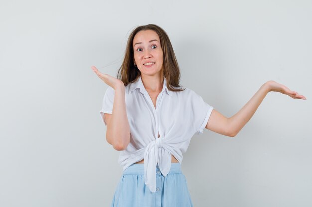 Young lady in blouse and skirt spreading her palms aside