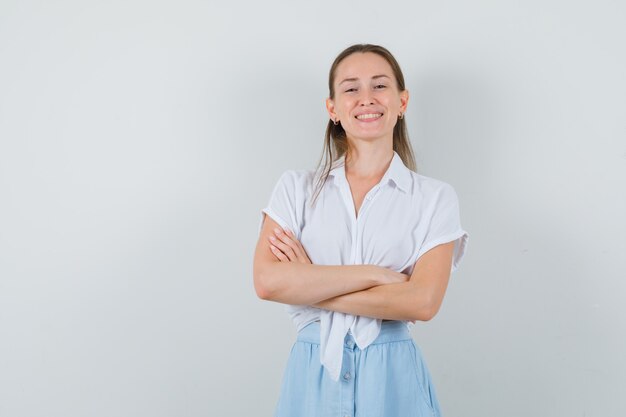 Young lady in blouse and skirt standing with crossed arms and looking confident