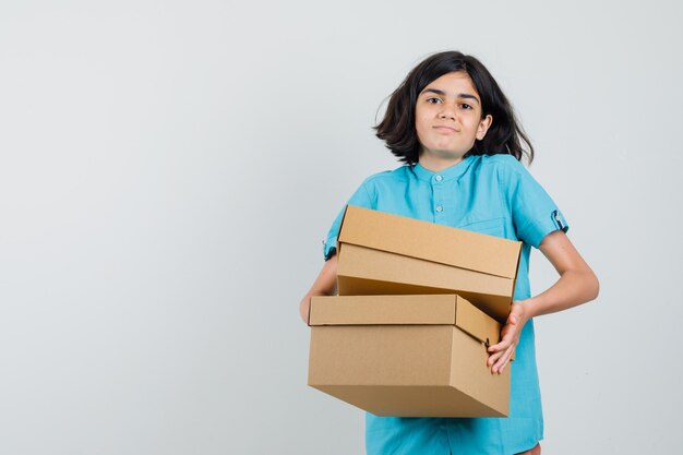 Молодая дама в голубой рубашке держит коробки