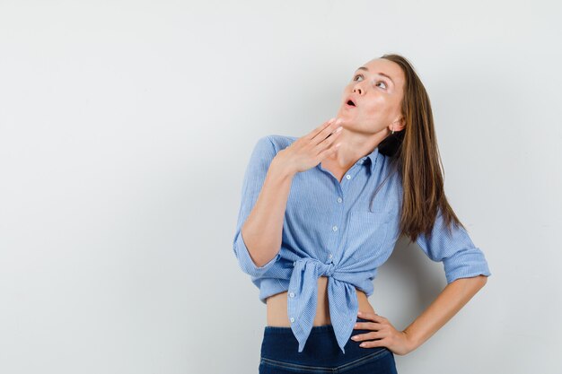 Young lady in blue shirt, pants looking up and looking astonished