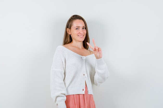 Young lady in cardigan and skirt showing victory gesture looking lucky isolated