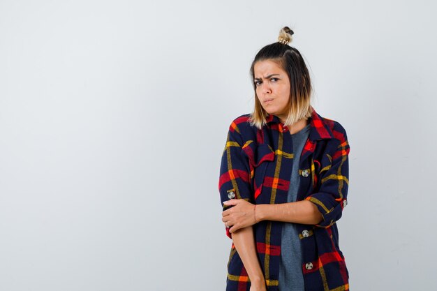 Young lady in casual checked shirt looking at camera and looking dismal , front view.