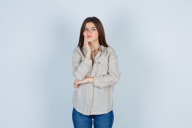 Young lady in casual, jeans suffering from toothache and looking unwell , front view.
