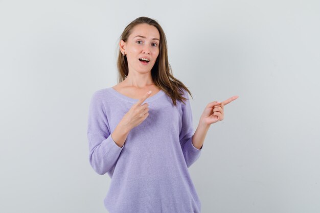 Young lady in casual shirt pointing aside and looking glad 