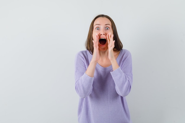 Young lady in casual shirt telling secret or announcing something and looking merry 