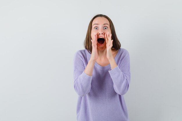 Young lady in casual shirt telling secret or announcing something and looking merry 