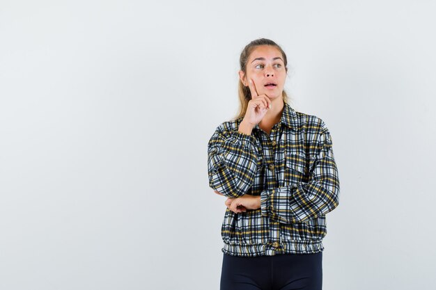 Young lady in checked shirt looking away and looking pensive , front view.