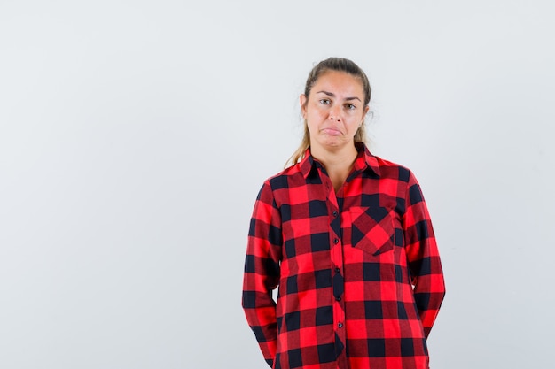 Young lady in checked shirt looking at front and looking upset