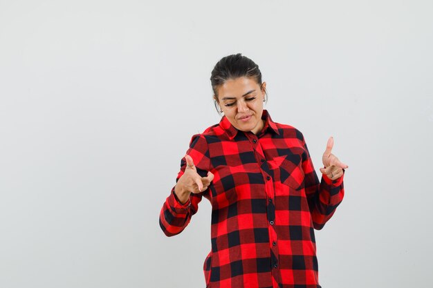 Young lady in checked shirt pointing down and looking focused