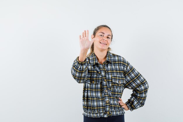 Young lady in checked shirt showing refusal gesture and looking confident , front view.