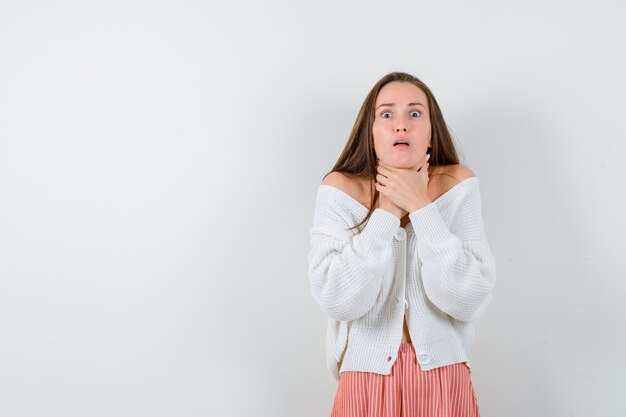 Young lady choking herself in cardigan and skirt looking unwell isolated