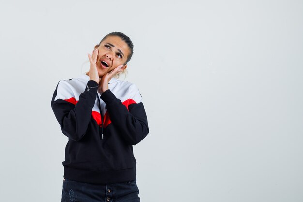 Young lady in colorful sweatshirt calling someone and looking focused , front view. 