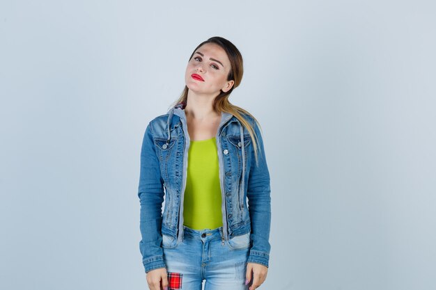 Young lady in denim outfit looking at front and looking delighted , front view.