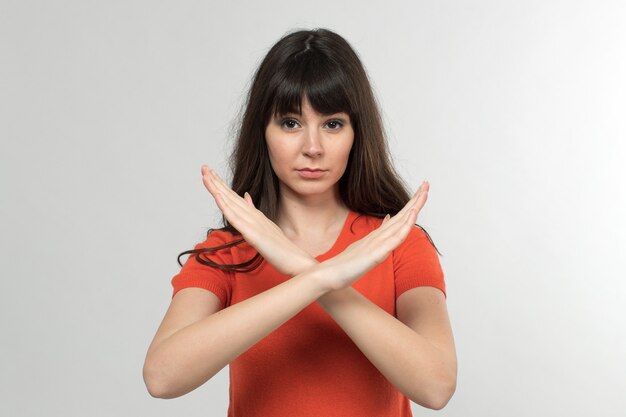 young lady in designed t-shirt showing no way sign with long hair on white