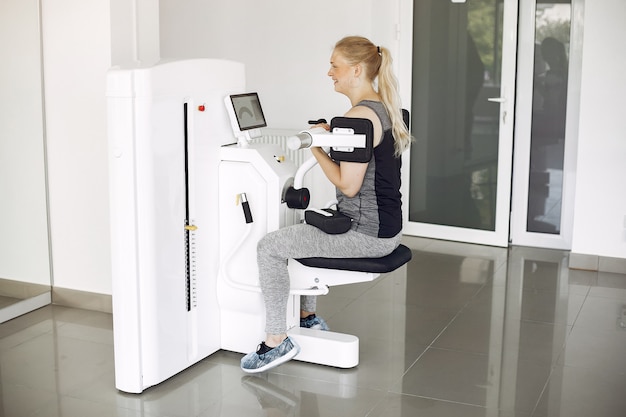 Young lady doing exercises on simulator in phisiotherapy room