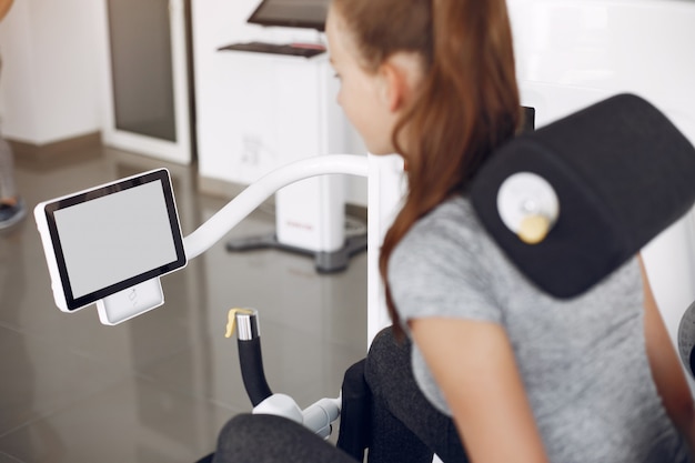 Free photo young lady doing exercises on simulator in phisiotherapy room