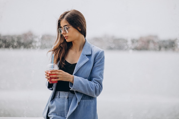 公園でアイスティーを飲む若い女性