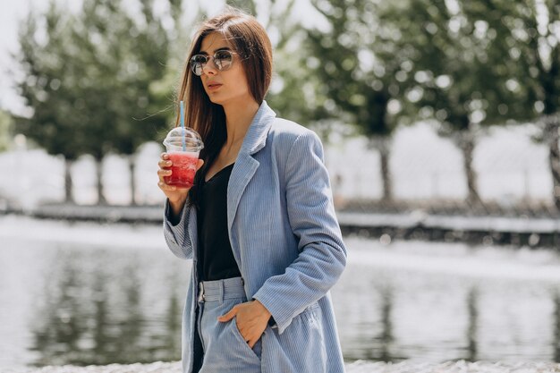 公園でアイスティーを飲む若い女性