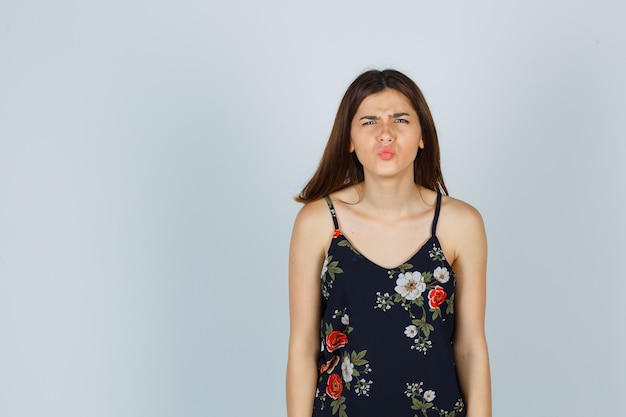 Free photo young lady in floral top and looking displeased