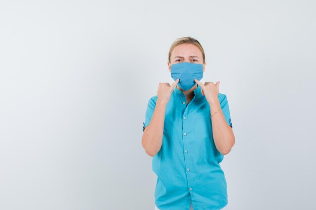 Young lady force a smile on face in t-shirt, mask and looking disappointed