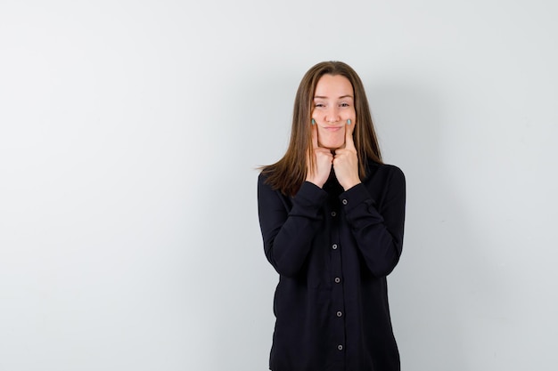 Young lady forcing a smile on face with fingers