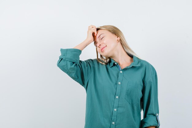 Young lady in green shirt keeping hand on head and looking peaceful