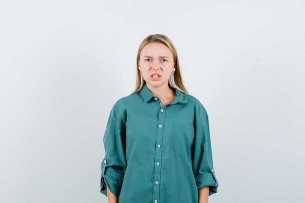 Giovane donna in camicia verde che guarda l'obbiettivo e sembra frustrata