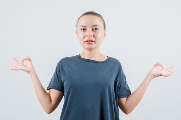 瞑想をして希望に満ちた灰色のTシャツの若い女性