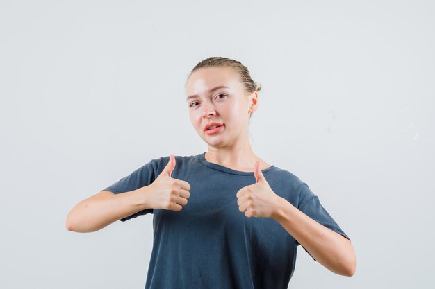 親指を立てて喜んでいる灰色のTシャツの若い女性