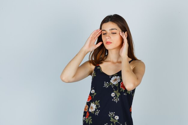 Young lady having headache in blouse and looking exhausted. front view.