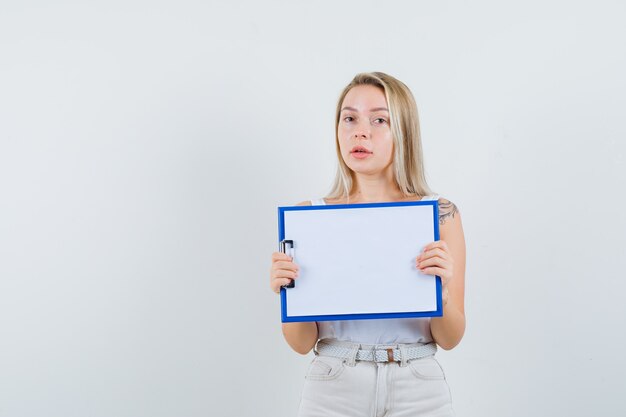Young lady holding blank clipboard in white blouse and looking ready
