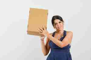 Free photo young lady holding cardboard box in dress and looking glad