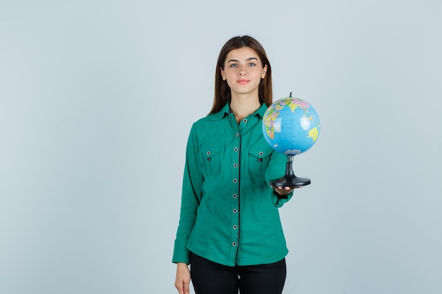 Young lady holding earth globe in shirt and looking confident , front view.