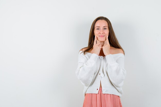 Young lady holding fingers on cheeks in cardigan isolated