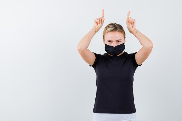 Young lady holding fingers over head as horns in t-shirt