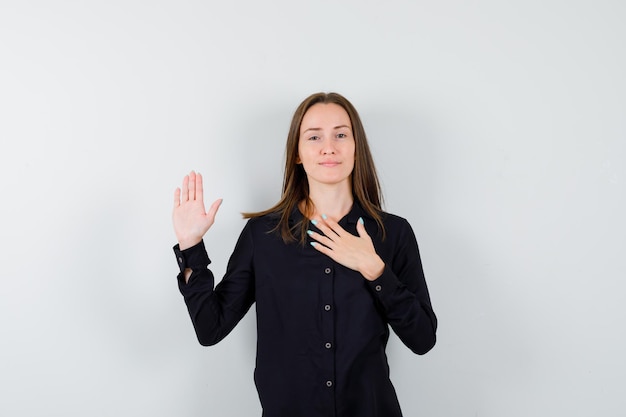 Free photo young lady holding hand on chest and showing palm