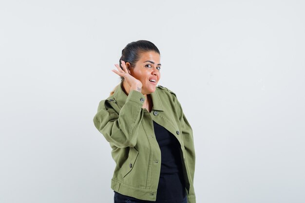 Young lady holding hand behind ear in t-shirt