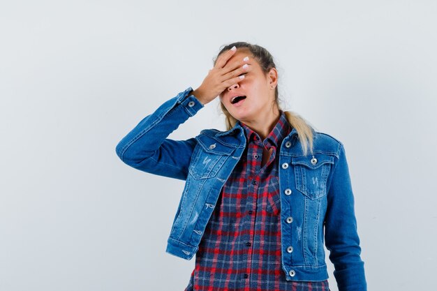 Young lady holding hand on eyes in shirt, jacket and looking elegant , front view.