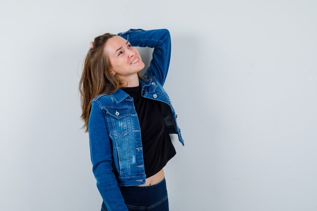 Young lady holding hand on head in blouse and looking dreamy , front view.