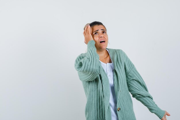 Young lady holding hand on head in t-shirt, jacket and looking confused