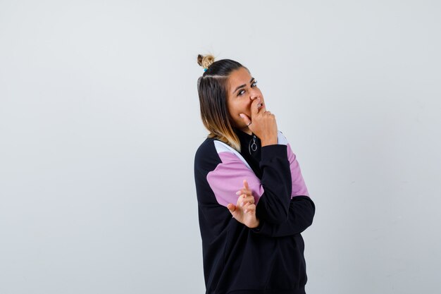 Young lady holding hand on mouth in hoodie sweater and looking confident.