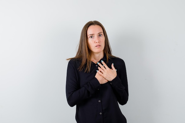 Young lady holding hands on chest and looking scared